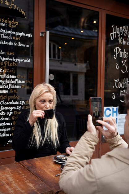 Senior man taking photos of woman at bistro