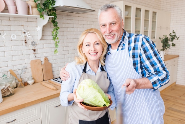 Senior man taking selfie with her wife holding cabbage in plate