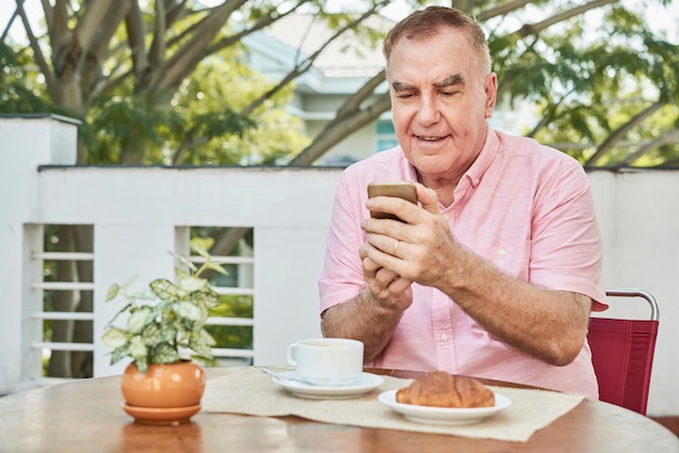 Senior man texting at the cafe