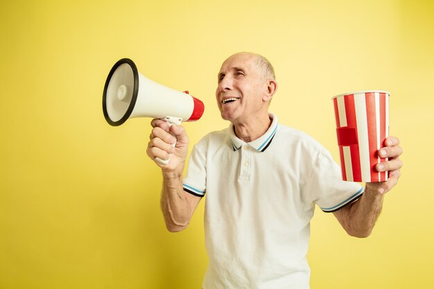 Senior man using megaphone and holding striped package