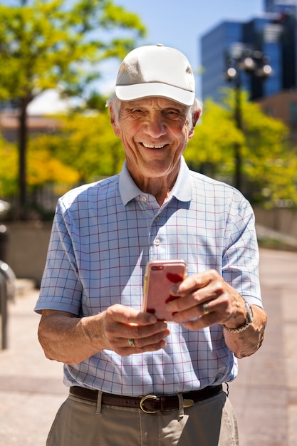 Бесплатное фото Старший мужчина с помощью смартфона во время прогулки на свежем воздухе