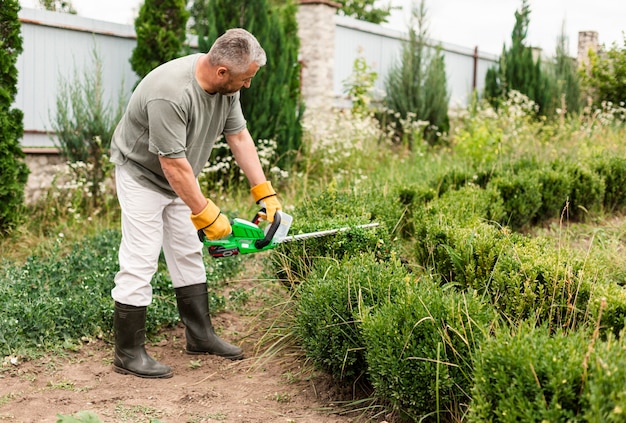 Senior man using trimming tool on bush