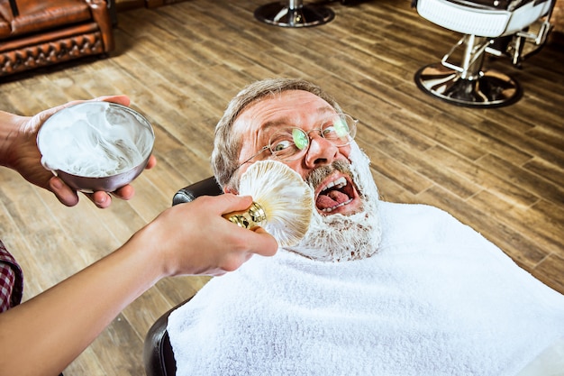 Free photo senior man visiting hairstylist in barber shop