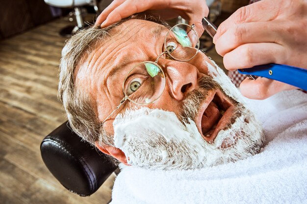 senior man visiting hairstylist in barber shop.