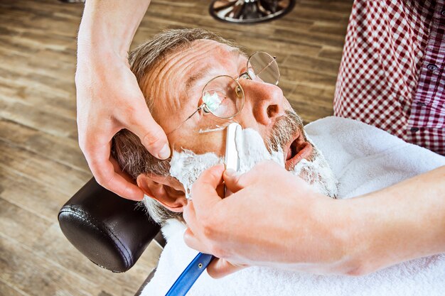 senior man visiting hairstylist in barber shop.