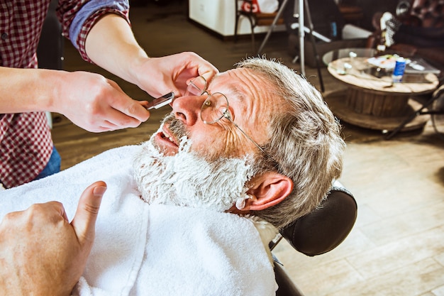 senior man visiting hairstylist in barber shop.