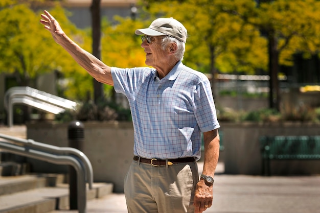 Free photo senior man waving while taking a walk outdoors