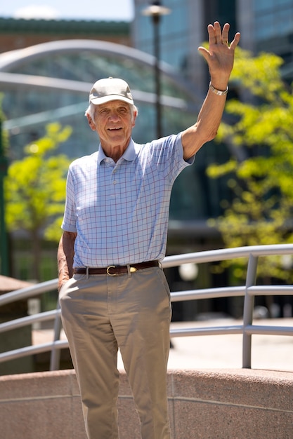 Старший мужчина машет рукой во время прогулки на свежем воздухе