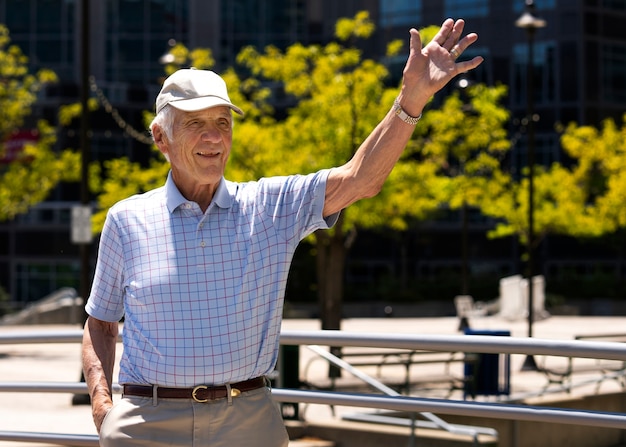 Free photo senior man waving while taking a walk outdoors