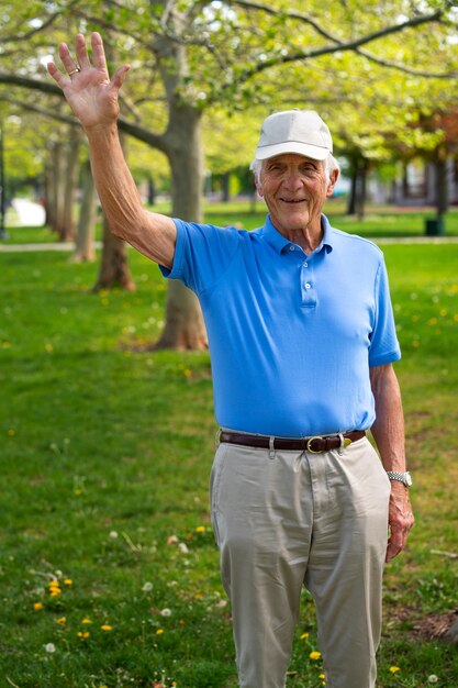 Старший мужчина машет рукой во время прогулки на свежем воздухе