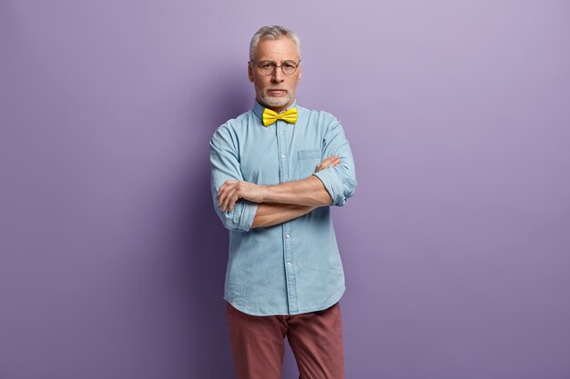 青いシャツと黄色の蝶ネクタイを着ている年配の男性