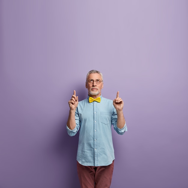 Free photo senior man wearing blue shirt and yellow bowtie