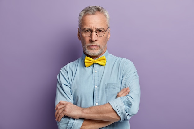 Senior man wearing blue shirt and yellow bowtie