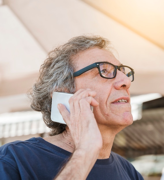 Foto gratuita occhiali d'uso dell'uomo senior che parlano sullo smartphone