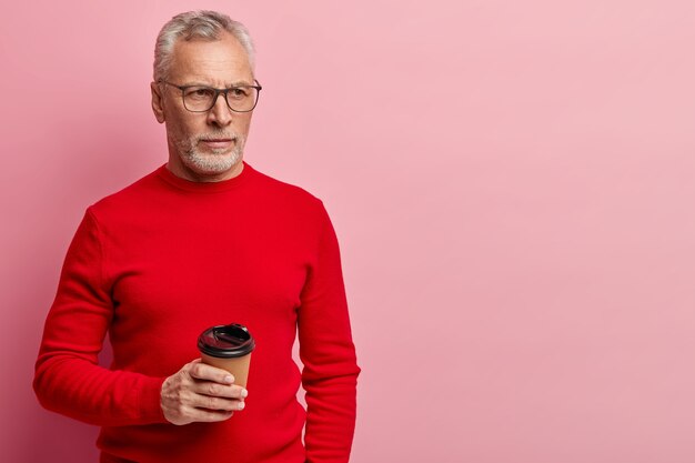 赤いセーターと流行の眼鏡をかけている年配の男性