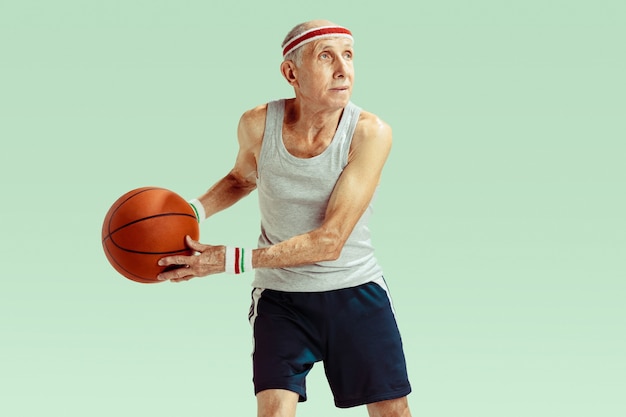 Free photo senior man wearing sportwear playing basketball on green