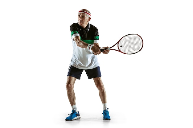 Senior uomo che indossa abbigliamento sportivo giocando a tennis su bianco