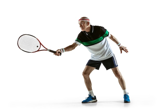 Senior man wearing sportwear playing tennis on white