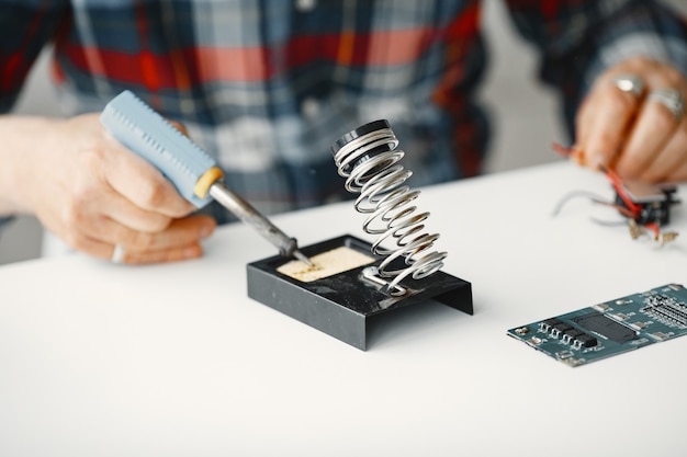 Senior man with equipment for soldering. Working at home.