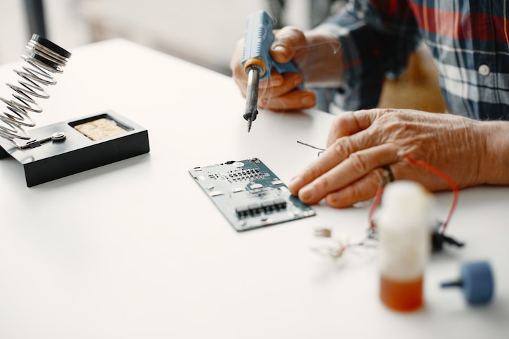 मुफ़्त फोटो senior man with equipment for soldering. working at home.