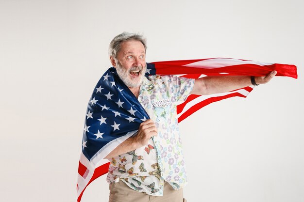 Senior man with the flag of the United States of America isolated on white studio.