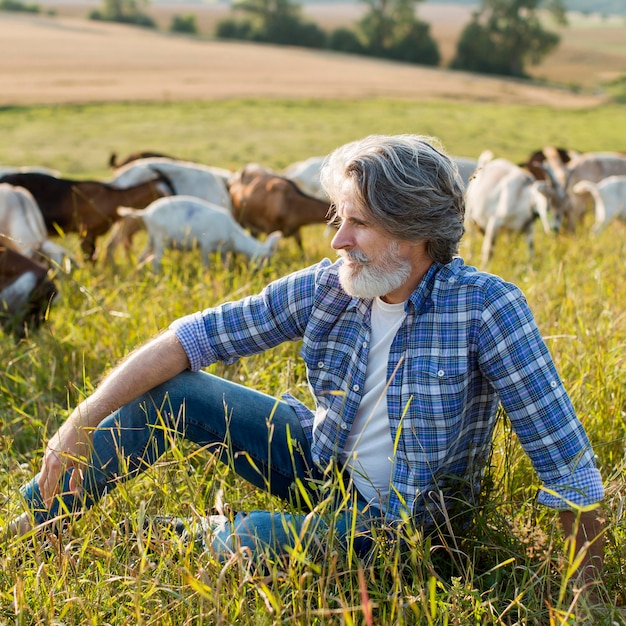 Foto gratuita uomo anziano con capre in fattoria