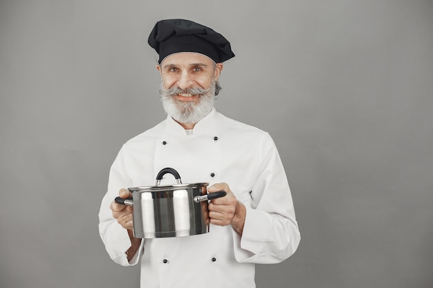 Foto gratuita uomo anziano con padella in metallo. chef con un cappello nero. approccio professionale al business.