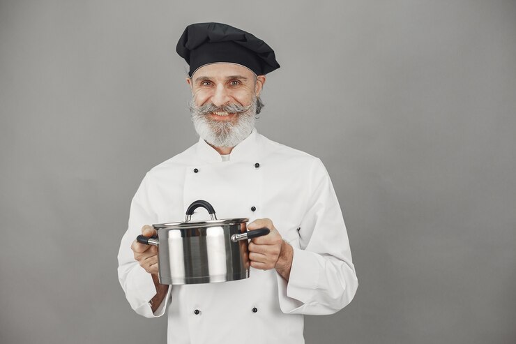 Free Photo senior man with metal pan. chef in a black hat. professional approach to business.