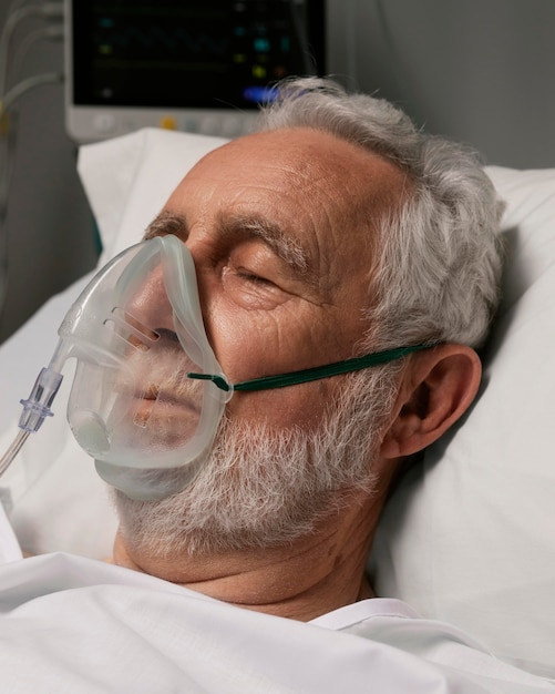 Foto gratuita uomo anziano con respiratore in un letto d'ospedale