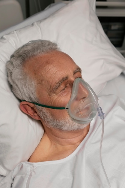 Foto gratuita uomo anziano con respiratore in un letto d'ospedale