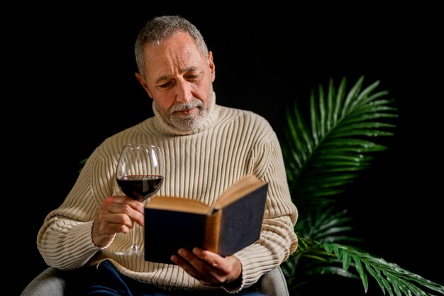 Старший мужчина с вином читает возле завода