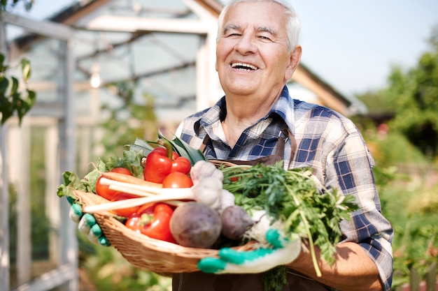 Foto gratuita uomo anziano che lavora nel campo con una cassa di verdure