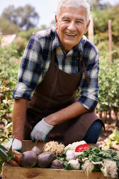 野菜と一緒に畑で働く年配の男性