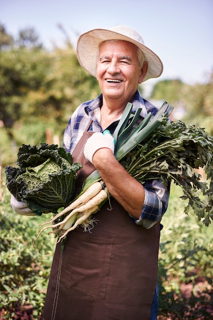 野菜と一緒に畑で働く年配の男性