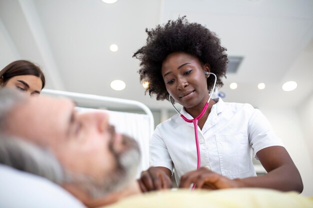 Senior patient on bed talking to African American female doctor in hospital room Health care and insurance concept Doctor comforting elderly patient in hospital bed or counsel diagnosis health