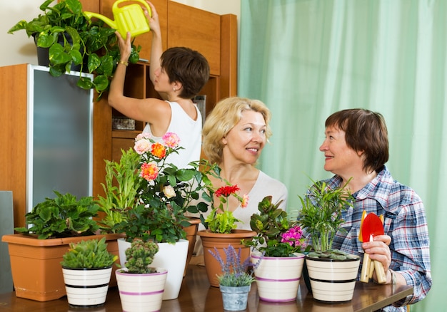 Pensionati senior e ragazza che si prendono cura delle piante domestiche
