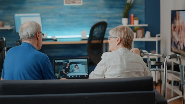 病院の親戚とのビデオ通話会議に参加する高齢者。オンラインリモートビデオ会議で家族とチャットするためにラップトップコンピューターを使用している祖父母。インターネット会話