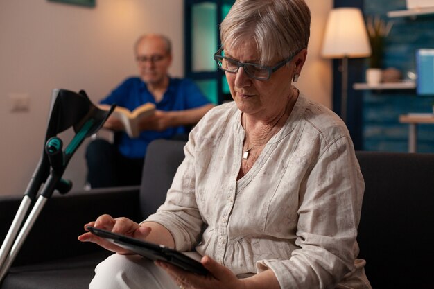 Senior person with crutches looking at modern tablet
