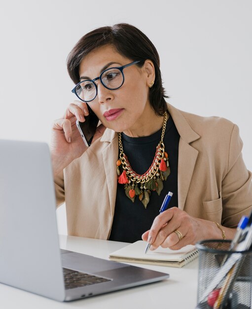 senior with necklace talking on the phone on her office