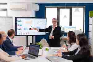 Free photo senior woman company leader brainstorming in conference room corporate staff discussing new business application with colleagues looking at screen