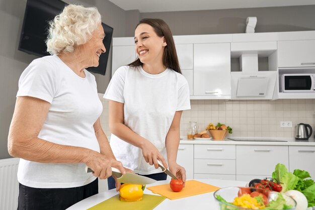 Senior woman cooking salad with granddaughter