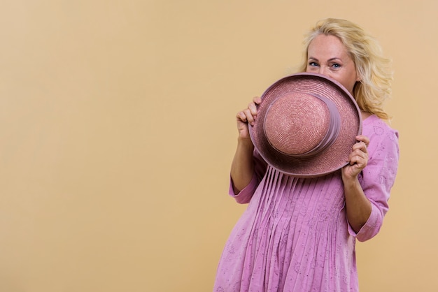 Free photo senior woman covering her face with a pink hat