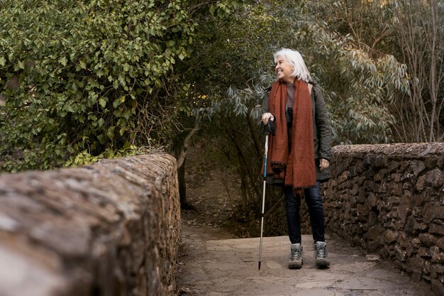Senior woman crossing a stone bridge while out in nature