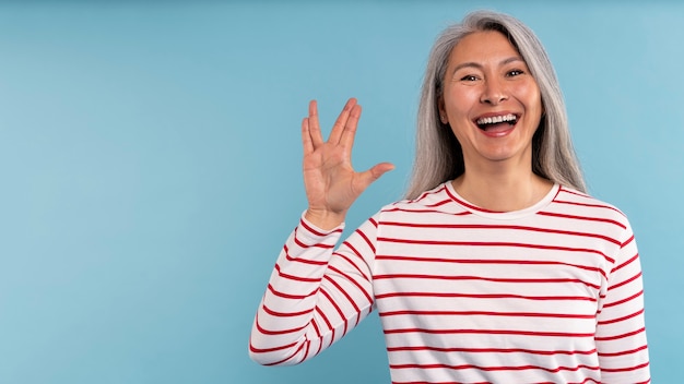 Senior woman doing the alien sign against a blue background