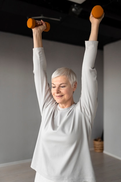 Foto gratuita senior donna facendo esercizi con i manubri in palestra