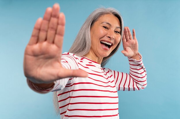 가라테를 하는 시니어 여성은 파란색 배경을 배경으로 움직입니다.