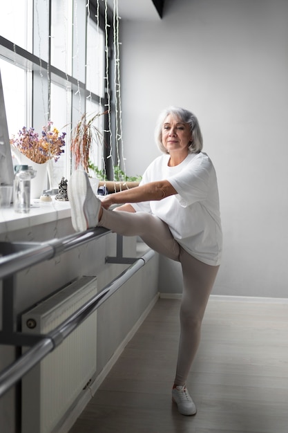 Free photo senior woman doing a warm-up at the gym