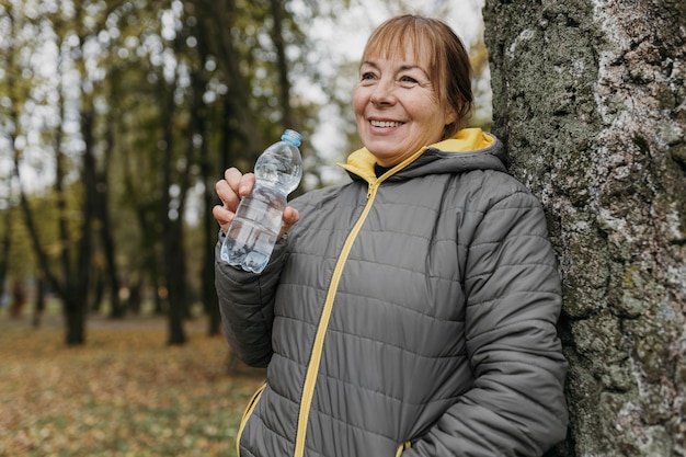 自然の中で運動した後、水を飲む年配の女性