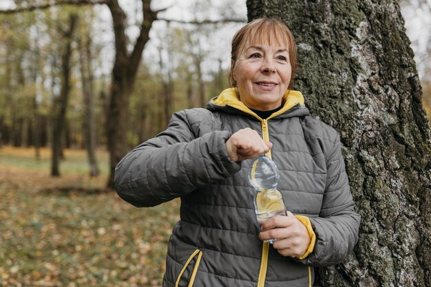 Senior woman drinking water after working out outdoors