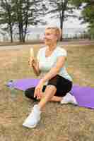 Foto gratuita senior donna mangiare banane all'aperto nel parco dopo lo yoga